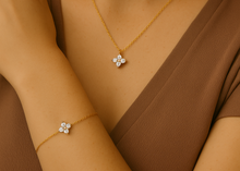 Load image into Gallery viewer, Model wearing the Floral Zircon Gold Bracelet and matching necklace by MJ Luxe. This dainty bracelet features delicate floral motifs with zircon stones on a polished gold chain, adding subtle sparkle and timeless charm. Designed to be lightweight, adjustable, and versatile, it transitions seamlessly from casual looks to special occasions. A thoughtful gift for women, bridesmaids, or loved ones who appreciate minimalist gold jewellery.