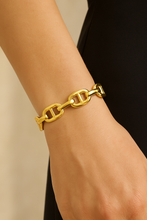 Load image into Gallery viewer, A woman wearing the Gold Chain-link Cuff Bracelet by MJ Luxe Co styled with a sleek black outfit. Featuring polished gold chain-style links in an open cuff design, this adjustable bracelet adds modern sophistication to any look. Lightweight and versatile, it’s perfect for everyday wear, stacking with other bangles, or wearing solo. A thoughtful jewelry gift for women, birthdays, anniversaries, or bridal parties.