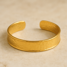 Load image into Gallery viewer, Flat lay of the MJ Luxe Co Colette Gold Textured Cuff Bracelet, crafted in 18K gold plated stainless steel with a hammered textured finish. This adjustable open cuff design is waterproof, tarnish resistant, hypoallergenic, and nickel free, making it perfect for everyday wear. A dainty yet durable gold bangle that makes a timeless jewellery gift for women, bridesmaids, or as a versatile minimalist bracelet.
