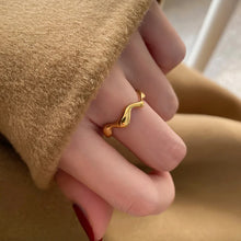 Load image into Gallery viewer, Minimalist Gold Wave Ring in 18K gold plating size 8 styled on model’s thumb, showing versatile sculptural design perfect for stacking, layering, or everyday wear.