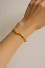 Load image into Gallery viewer, Model wearing Chloe Gold Wave Cuff Bracelet on wrist, minimalist sculptural open bangle, modern gold jewelry for stacking and everyday style.
