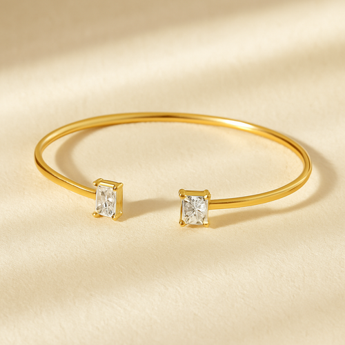 Gold Duo Diamond Cuff Bracelet displayed on soft stone surface, featuring one square-cut and one rectangular diamond-inspired zircon stone set on a polished open gold band. Minimalist cuff bracelet for women by MJ Luxe, designed for everyday wear and modern styling.