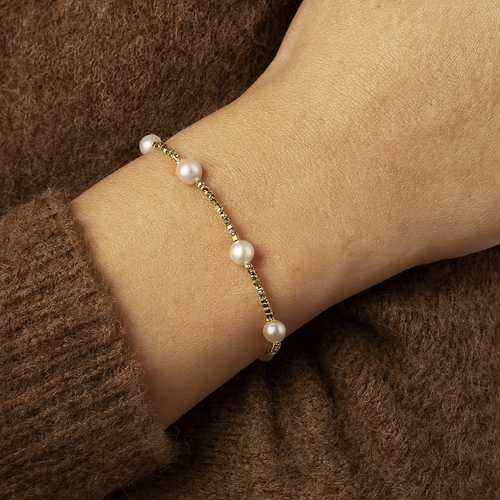 Elise Gold Pearl Beaded Bracelet worn on wrist with brown knitwear, dainty gold and pearl bracelet for women by MJ Luxe, minimalist waterproof and tarnish resistant jewellery design.