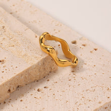 Load image into Gallery viewer, Gold Wave Ring in 18K gold plated stainless steel displayed on natural stone background, featuring sculptural wavy band design for minimalist jewellery styling.
