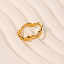 Load image into Gallery viewer, Polished Gold Wave Ring in 18K gold plated stainless steel photographed on textured neutral surface, highlighting sculptural wave curves and glossy shine.
