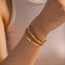 Load image into Gallery viewer, Minimalist hammered double cuff bracelet in waterproof 18K gold plating, modeled for a lifestyle look. The double-band design with hammered texture creates a bold yet elegant statement. Adjustable open cuff style ensures long-lasting comfort and fit. A tarnish-resistant, stackable bracelet crafted for modern women who love timeless jewellery. Ideal for everyday wear or as a meaningful gift from MJ Luxe.
