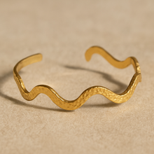 Load image into Gallery viewer, Close-up of MJ Luxe Hammered Gold Wave Cuff Bracelet, textured hammered finish with modern wave pattern, timeless cuff jewelry.
