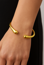 Load image into Gallery viewer, Model wearing MJ Luxe Ava Gold Cuff Bracelet on wrist, open sculptural bangle in polished gold, styled with modern minimalist outfit.
