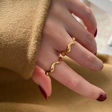 Load image into Gallery viewer, Two Gold Wave Rings in 18K gold plating stacked together on model’s hand, styled as layered minimalist jewellery for women who love modern gold rings.
